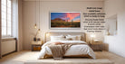 The image is a bedroom with a large bed, a nightstand, and a painting of a desert landscape hanging on the wall. The painting is framed in a 34x64-inch frame, which is available unframed, and it is ready to hang. The frame is showing a float frame, which is for canvas, metal, and acrylic prints. The frame has a champagne color, and it is wide enough to display more frame colors in Framing Options.