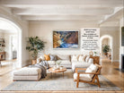 The image is a large framed photograph of a mountainous landscape, hanging on the wall of a living room.