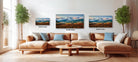 a living room with a large sectional sofa, a coffee table, and three framed landscape paintings hanging on the wall above the sofa.