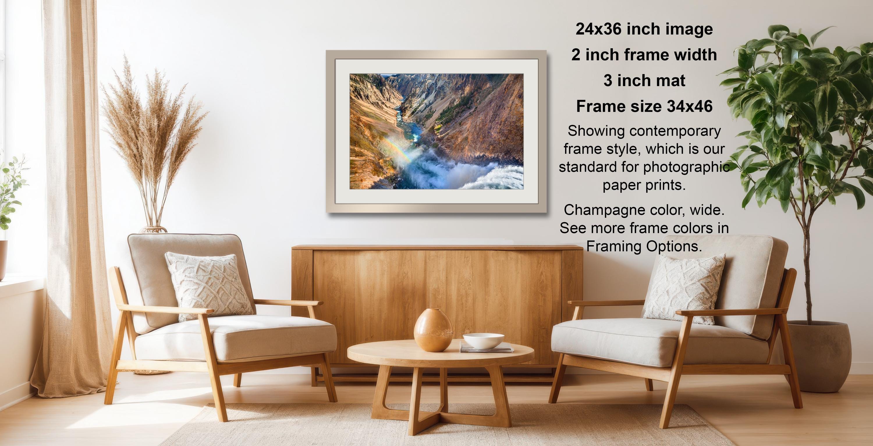 a living room with a wooden coffee table, two white armchairs, and a framed photograph of a waterfall hanging on the wall.