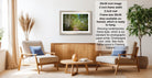 The image is a living room with two chairs, a coffee table, and a framed picture of a forest. The picture is framed in a modern style and hangs on the wall.