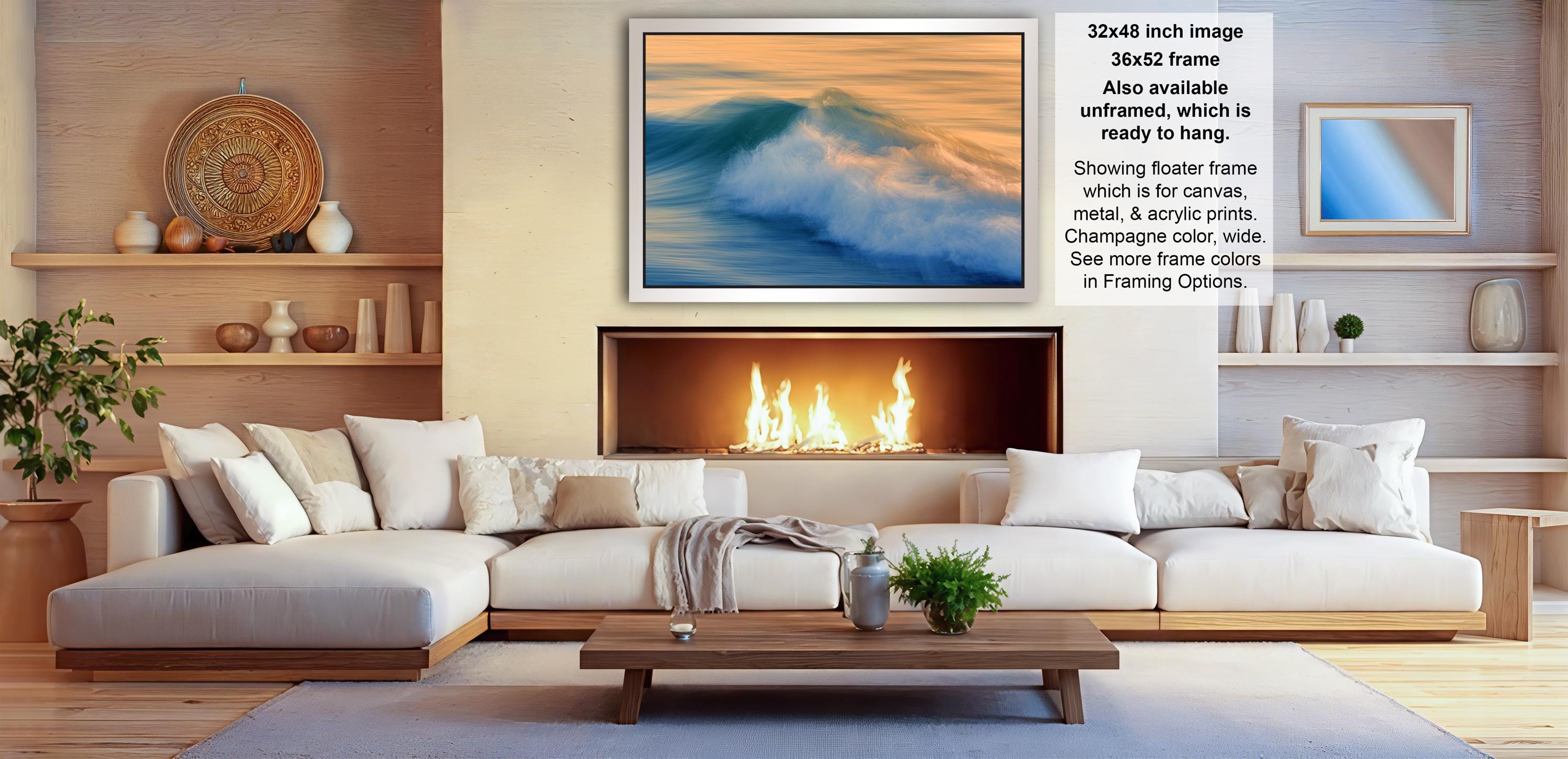 a cozy living room with a fireplace, white sofas, and a coffee table. The room has a warm and inviting atmosphere, with a large framed picture of a crashing wave hanging on the wall.