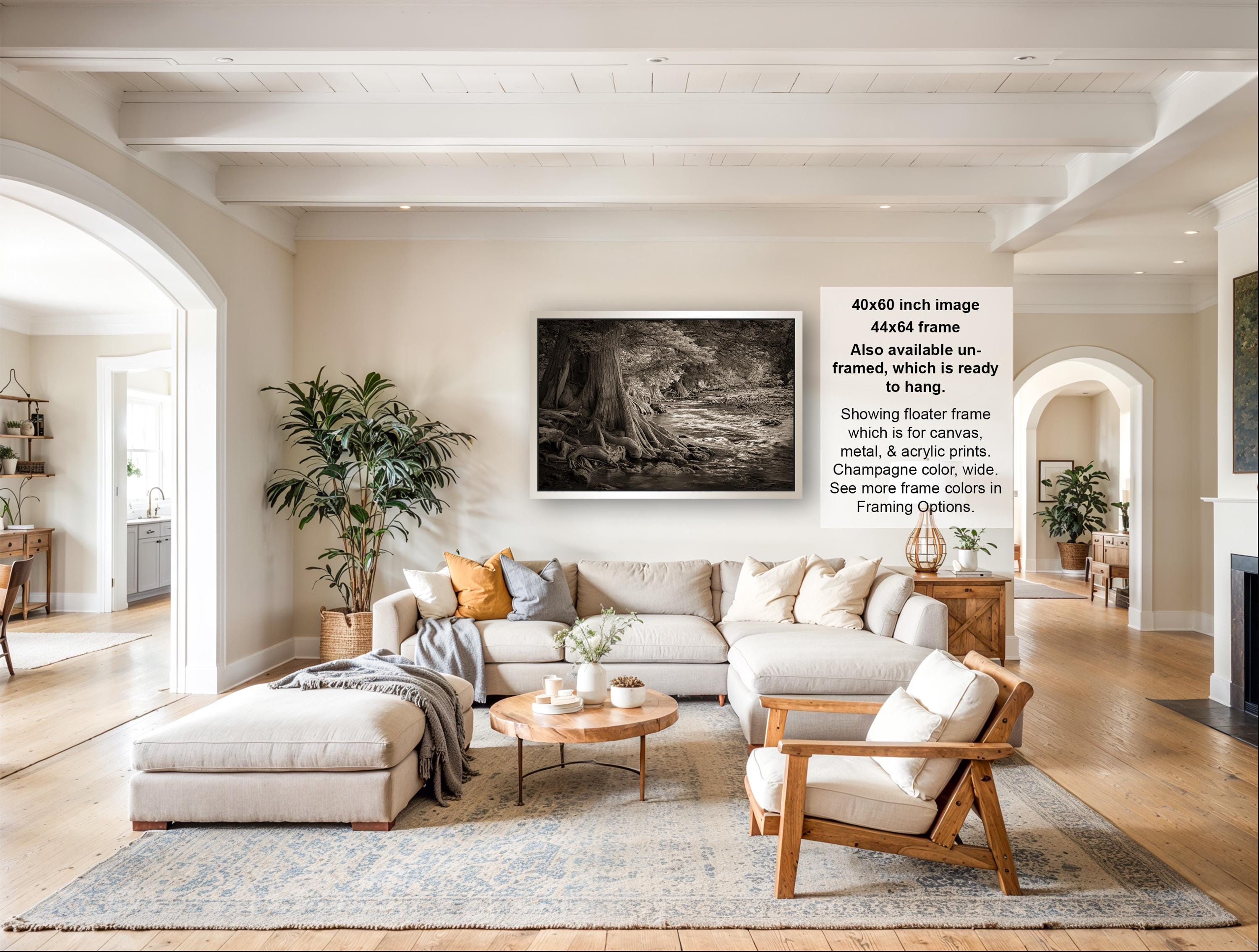 The image is a spacious living room with a large sectional sofa, a coffee table, and a fireplace. The room is decorated with various plants and has a neutral color palette.