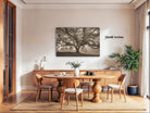 a cozy dining room with a large tree painting hanging on the wall above a wooden table surrounded by chairs.