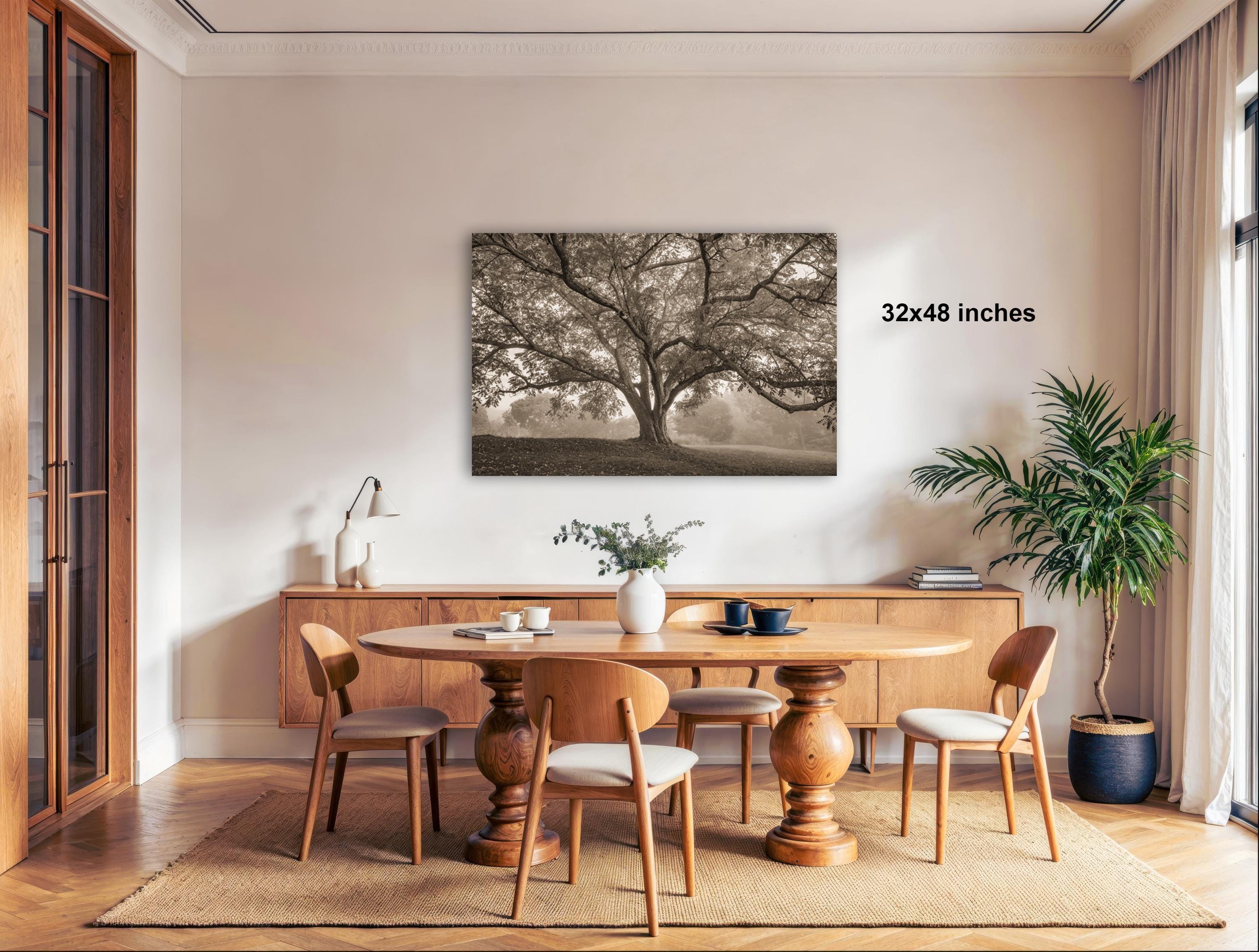 a cozy dining room with a large tree painting hanging on the wall above a wooden table surrounded by chairs.
