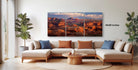 a living room with a large, three-part landscape painting hanging on the wall. The painting features a scenic view of a desert landscape with mountains in the background.