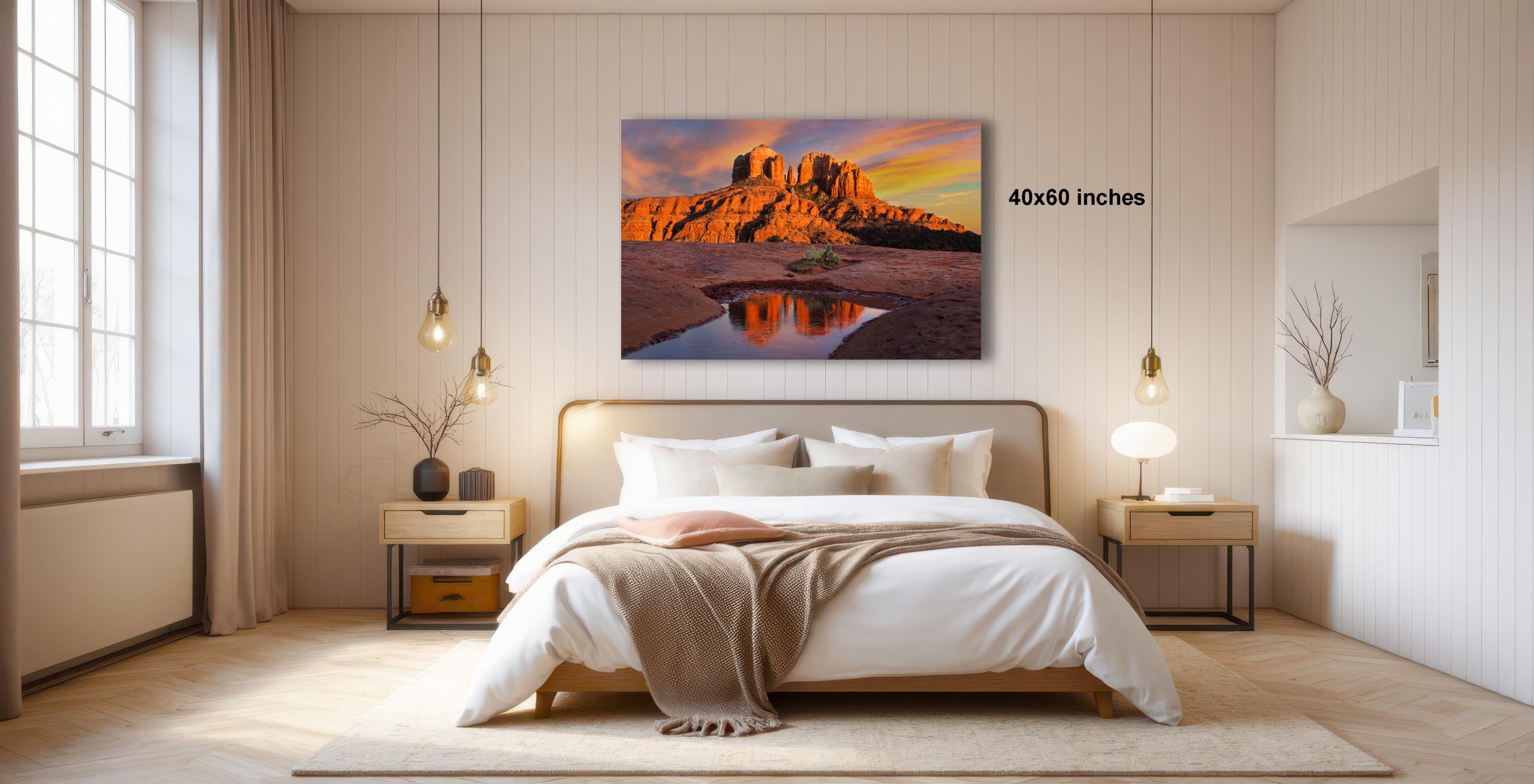a serene bedroom with a large bed, a nightstand, and a painting of a desert landscape hanging on the wall.