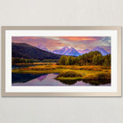 A framed landscape photograph depicting a serene mountain range with a lake and autumn foliage in the foreground.