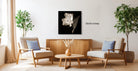 a living room with two armchairs, a wooden coffee table, and a framed artwork of a flower on the wall.