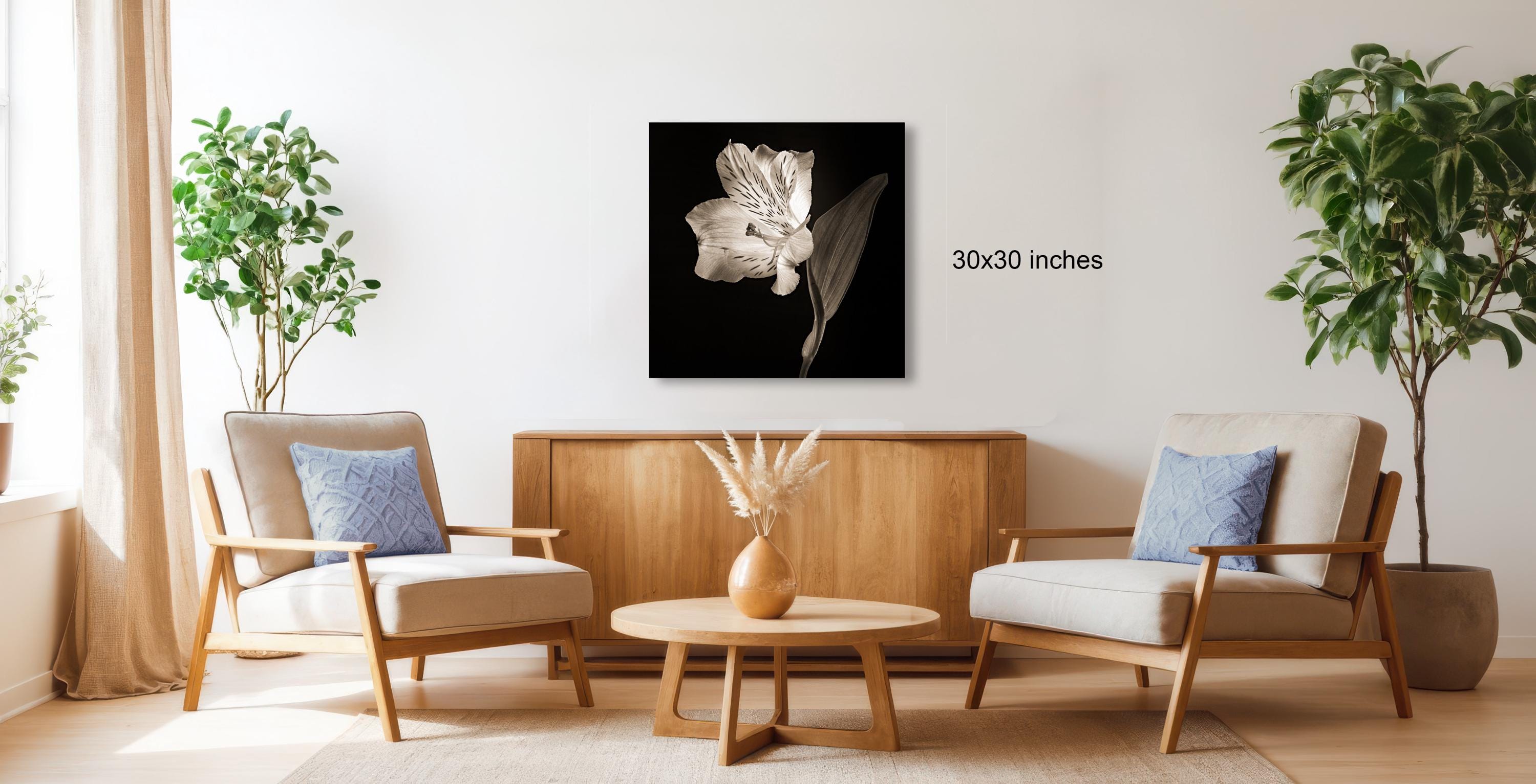 a living room with two armchairs, a wooden coffee table, and a framed artwork of a flower on the wall.