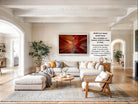 The image is a large, high-quality photograph of a living room with a large, framed artwork depicting a canyon or desert landscape. The room has a neutral color scheme with white walls, a gray rug, and a wooden coffee table. The furniture includes a sofa, armchairs, and a wooden side table. The room also features several potted plants and decorative items, creating a cozy and inviting atmosphere.