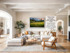 The image is a large framed landscape painting depicting a serene countryside scene with a field of flowers and a mountain backdrop.