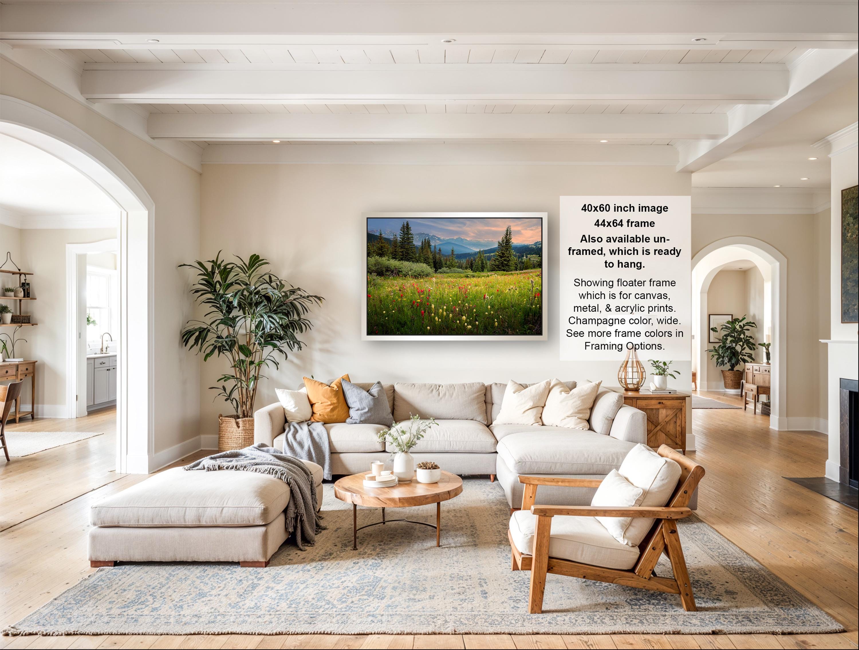 The image is a large framed landscape painting depicting a serene countryside scene with a field of flowers and a mountain backdrop.