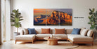 a large, three-panel landscape painting depicting a scenic mountain range at sunset.