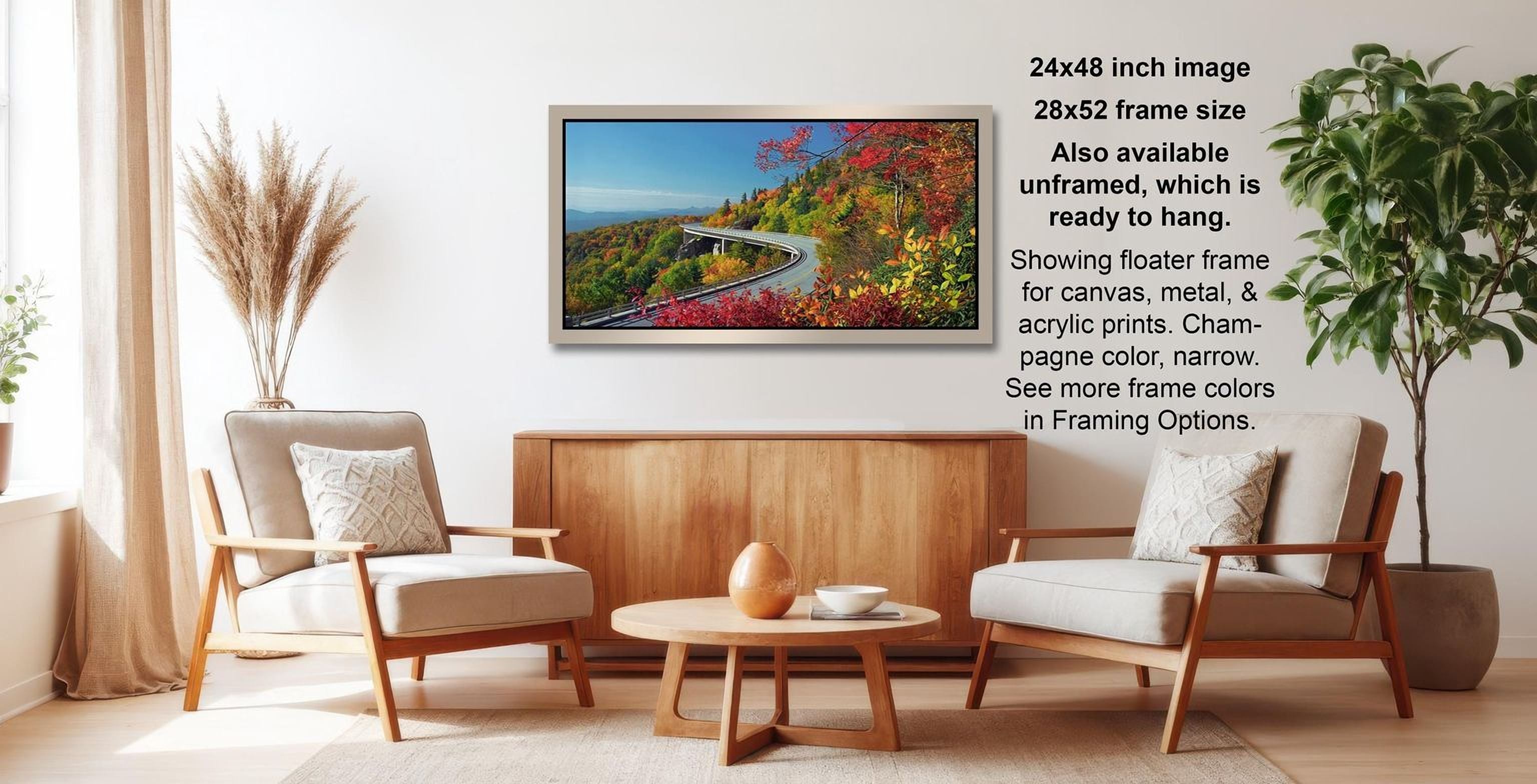 The image is a living room with a large framed landscape photograph hanging on the wall, featuring a winding road surrounded by trees and foliage. The room is furnished with two chairs and a coffee table, creating a cozy and inviting atmosphere.