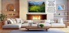 a cozy living room with a fireplace, white sofas, and a coffee table. The room has a warm and inviting atmosphere, with a fireplace providing a focal point and a painting of a field of flowers hanging above it.