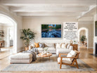 The image is a large framed picture of a river with water flowing over rocks, hanging on a wall in a living room.
