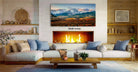a cozy living room with a fireplace, a large landscape painting hanging on the wall, and a wooden coffee table in front of the fireplace.