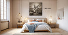 A modern bedroom with a large bed, wooden furniture, and a large black and white photograph of a tree hanging on the wall.