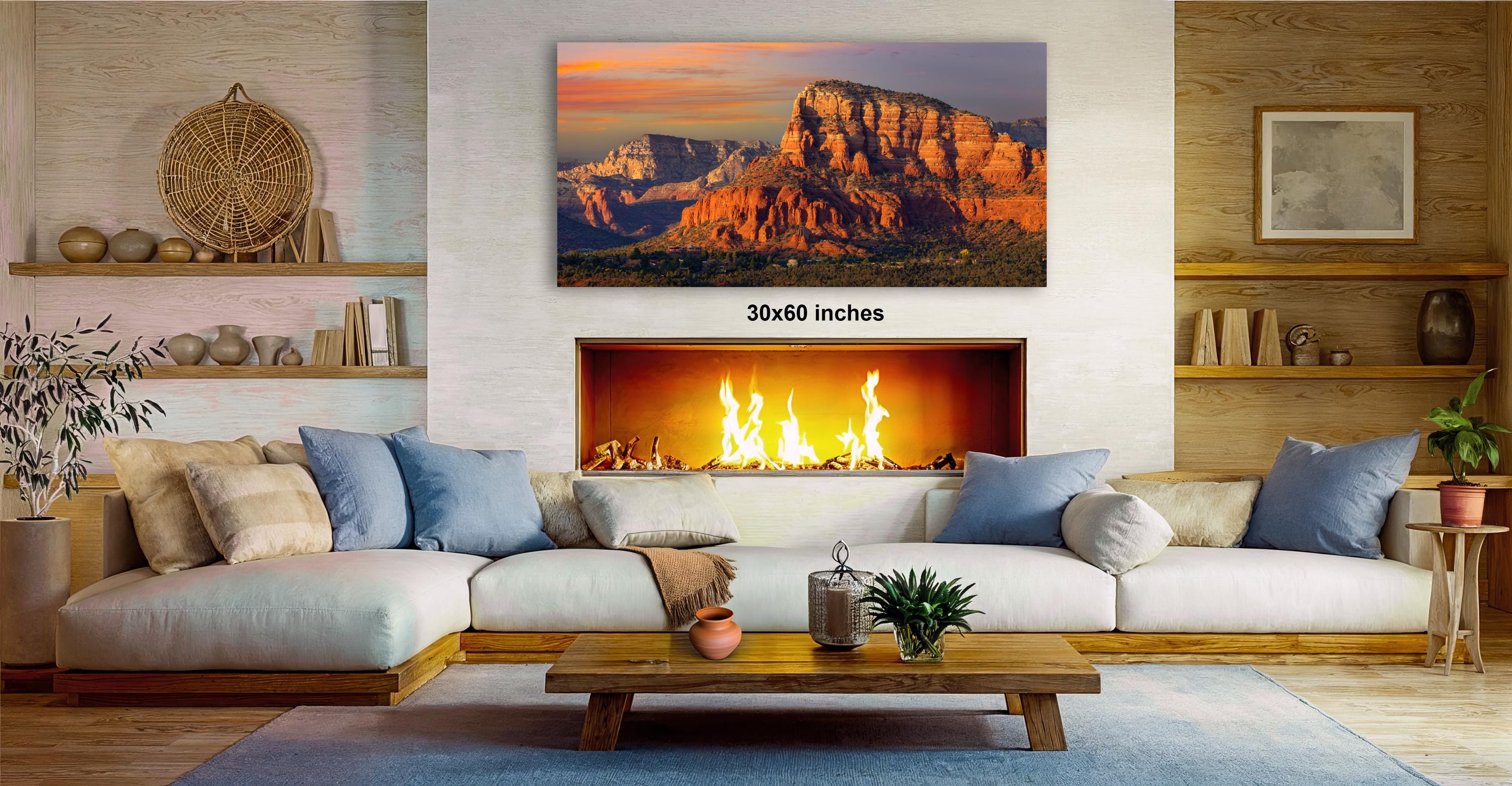 a cozy living room with a fireplace, a large framed landscape painting depicting a mountain range, and a wooden coffee table in front of the fireplace.