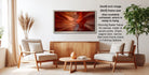 a modern living room with a large framed photograph of a canyon landscape hanging on the wall. The photograph has a reddish-orange hue and is framed in a 28x42-inch silver frame. The room is furnished with two beige armchairs and a wooden coffee table, creating a cozy and inviting atmosphere.