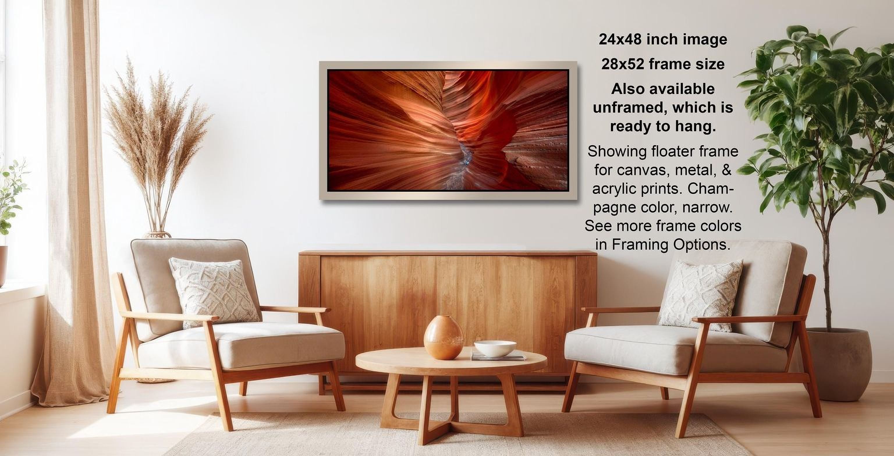 a modern living room with a large framed photograph of a canyon landscape hanging on the wall. The photograph has a reddish-orange hue and is framed in a 28x42-inch silver frame. The room is furnished with two beige armchairs and a wooden coffee table, creating a cozy and inviting atmosphere.