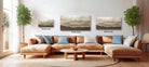 a cozy living room with a large sectional sofa, a coffee table, and three landscape paintings hanging on the wall.