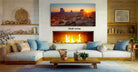 a cozy living room with a fireplace, a large framed landscape photograph of the desert at sunset, and a wooden coffee table.