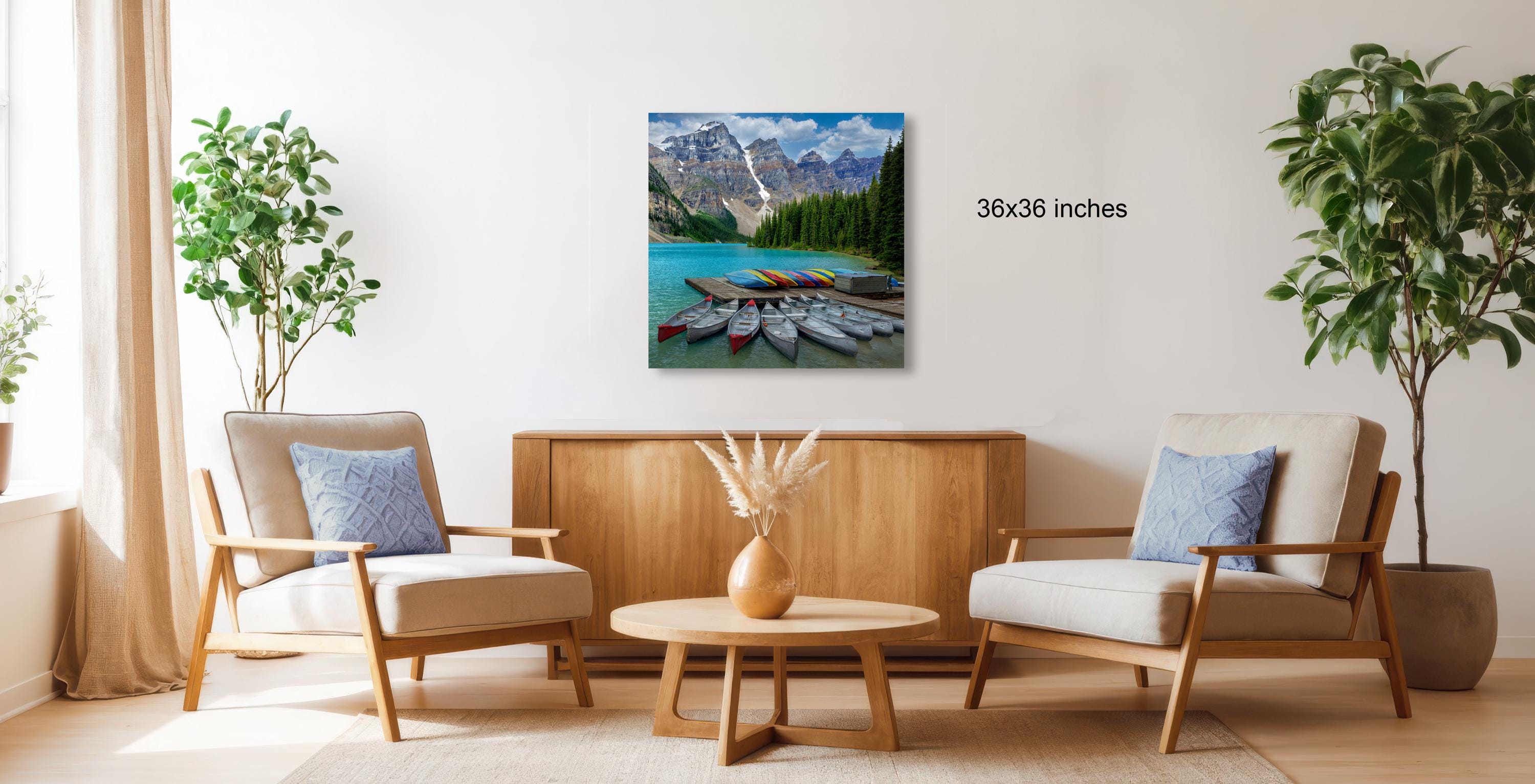 a living room with a large painting of a mountain lake hanging on the wall, surrounded by two chairs and a coffee table.