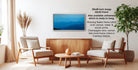 a living room with a wooden coffee table, two white armchairs, and a wooden sideboard. Above the coffee table is a framed picture of a mountain landscape. The room has a minimalist and modern design, with a large window providing natural light and a potted plant adding a touch of greenery.