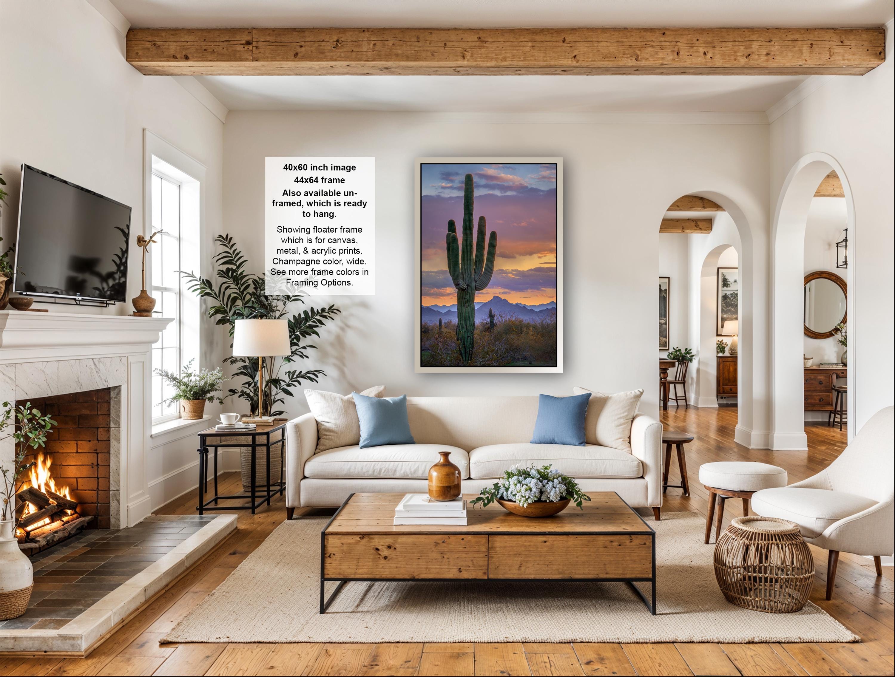 a cozy living room with a fireplace, a large framed picture of a cactus, and a wooden coffee table.