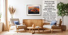 a living room with a framed landscape photograph hanging on the wall, a wooden coffee table in the center, and two chairs facing each other.
