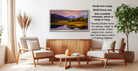 a living room with a large framed landscape painting hanging on the wall. The painting depicts a serene mountain landscape with a lake and trees. The room is furnished with two chairs and a coffee table, creating a cozy and inviting atmosphere.