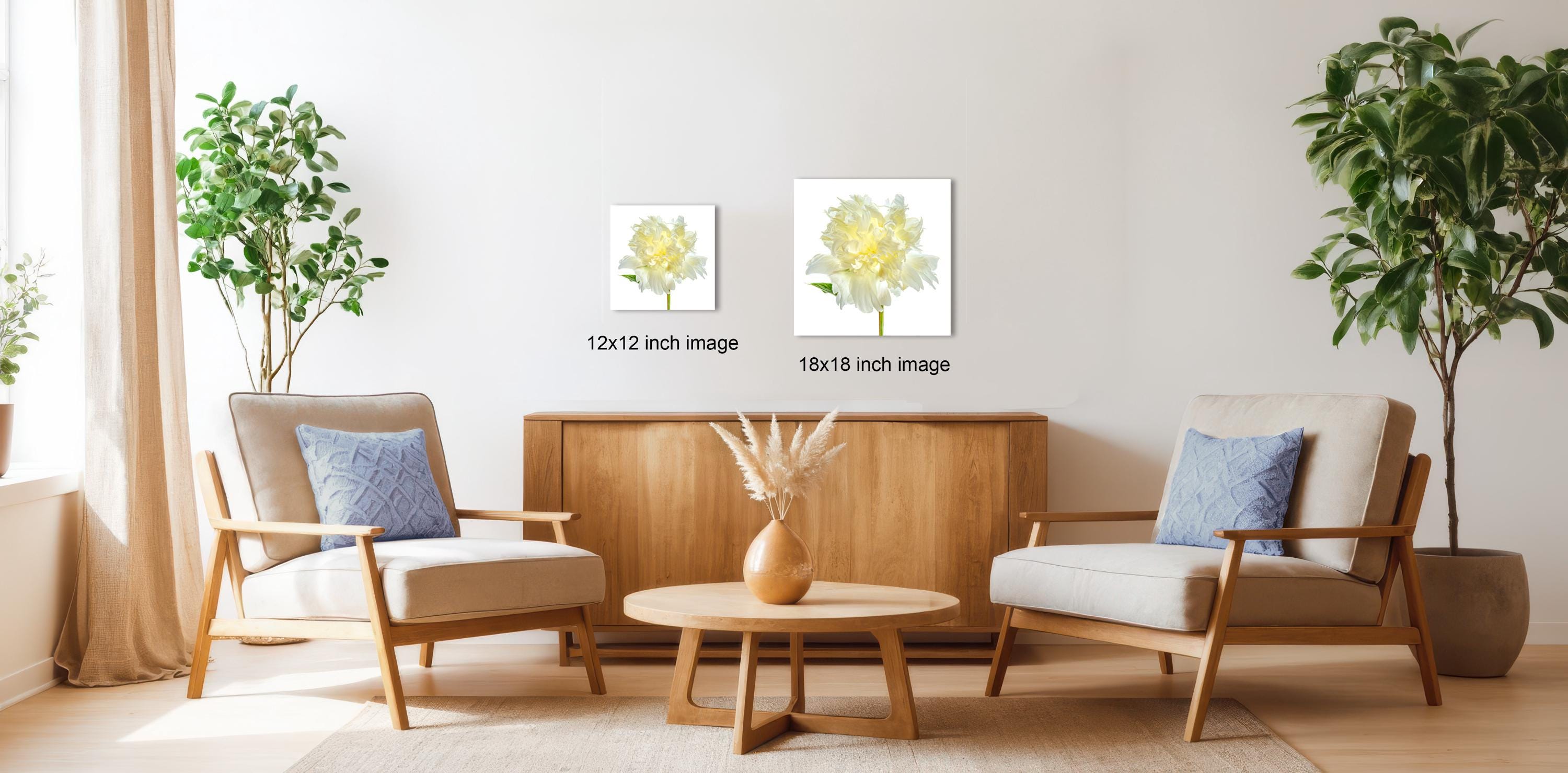 a cozy living room with two beige armchairs, a wooden coffee table, and a wooden sideboard. The room is decorated with potted plants and a vase of flowers, creating a warm and inviting atmosphere.