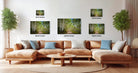 The image is a modern living room with a large sectional sofa, a coffee table, and several potted plants. The wall behind the sofa is decorated with three framed landscape photographs, each varying in size and resolution. The photographs depict different scenes, including a forest path and a wooded area. The arrangement of the photographs and the overall composition of the room create a harmonious and visually appealing space.