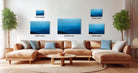 a living room with a large sectional sofa, a coffee table, and several framed landscape photographs displayed on the wall.