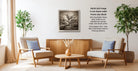 a cozy living room with two beige armchairs, a wooden coffee table, and a framed black and white landscape photograph hanging on the wall.