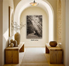 a hallway with a large black and white photograph of a winding road with sunlight streaming through the trees on the wall.