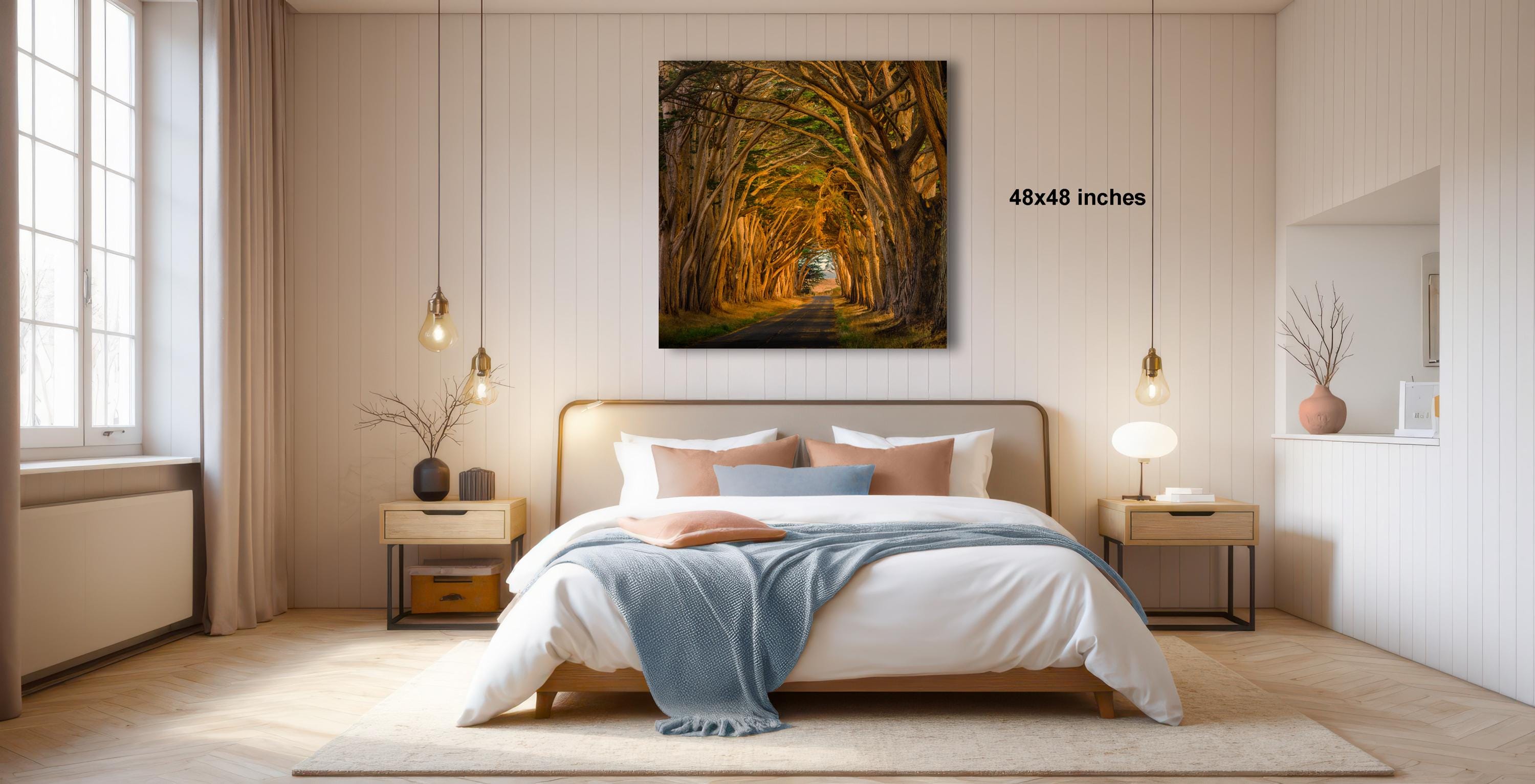 A modern bedroom with a large bed, wooden furniture, and a framed landscape photograph hanging on the wall.