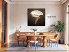 a modern dining room with a large, minimalist white flower on the wall as the focal point. The room is furnished with a wooden dining table surrounded by matching chairs, and a potted plant adds a touch of greenery to the space. The overall design and decor create a clean, elegant atmosphere.