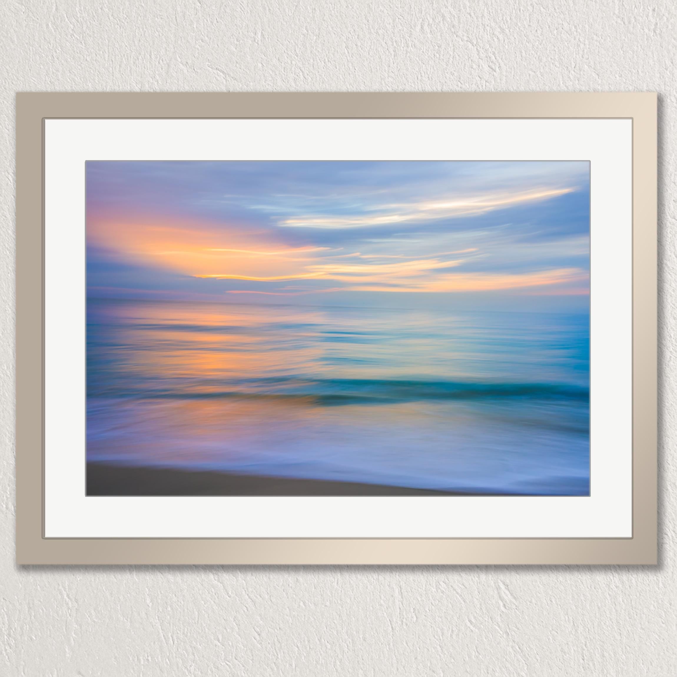 The image is a framed photograph of a serene beach scene with a calm ocean and a colorful sunset sky.