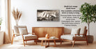 a living room with a wooden coffee table, two white armchairs, and a framed black and white photograph of a mountain landscape hanging on the wall.