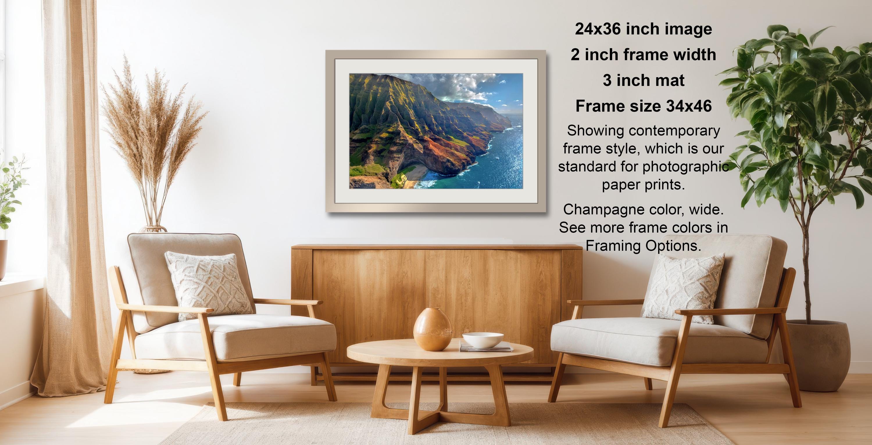 a living room with a wooden coffee table, two white armchairs, and a framed landscape photograph hanging on the wall.