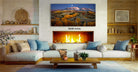a cozy living room with a fireplace, a large framed landscape painting on the wall, and a wooden coffee table in front of the fireplace.