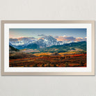 a breathtaking mountainous landscape with snow-capped peaks, a vibrant valley, and a clear blue sky with wispy clouds.
