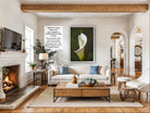 a cozy living room with a fireplace, a large framed print of a white lily on the wall, a wooden coffee table, and a comfortable sofa.