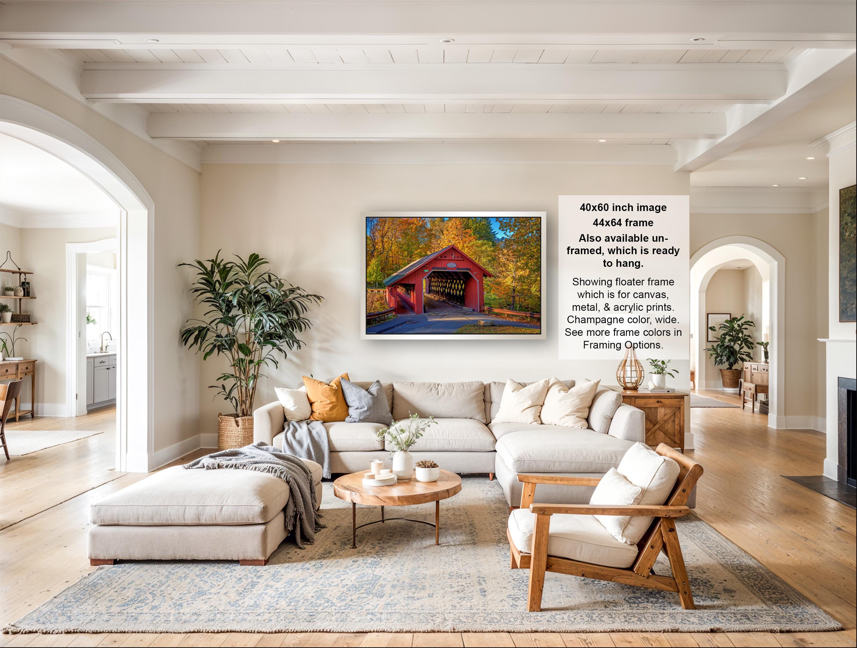 a large, comfortable living room with a cozy sectional sofa, a coffee table, and a fireplace. The room is decorated with various plants and has a rustic charm. The focal point of the room is a framed photograph of a red wooden bridge, which adds a pop of color to the space. The image also includes text that provides information about the frame size, material, and framing options.