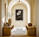 The image is a 32x48-inch framed photograph of a white flower in a black and white frame, hanging on a wall in a room with wooden furniture and decorative items.