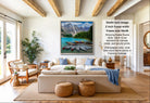 a living room with a large framed picture of a scenic mountain landscape hanging on the wall. The room is furnished with a sofa, chairs, and a coffee table, creating a cozy and inviting atmosphere.
