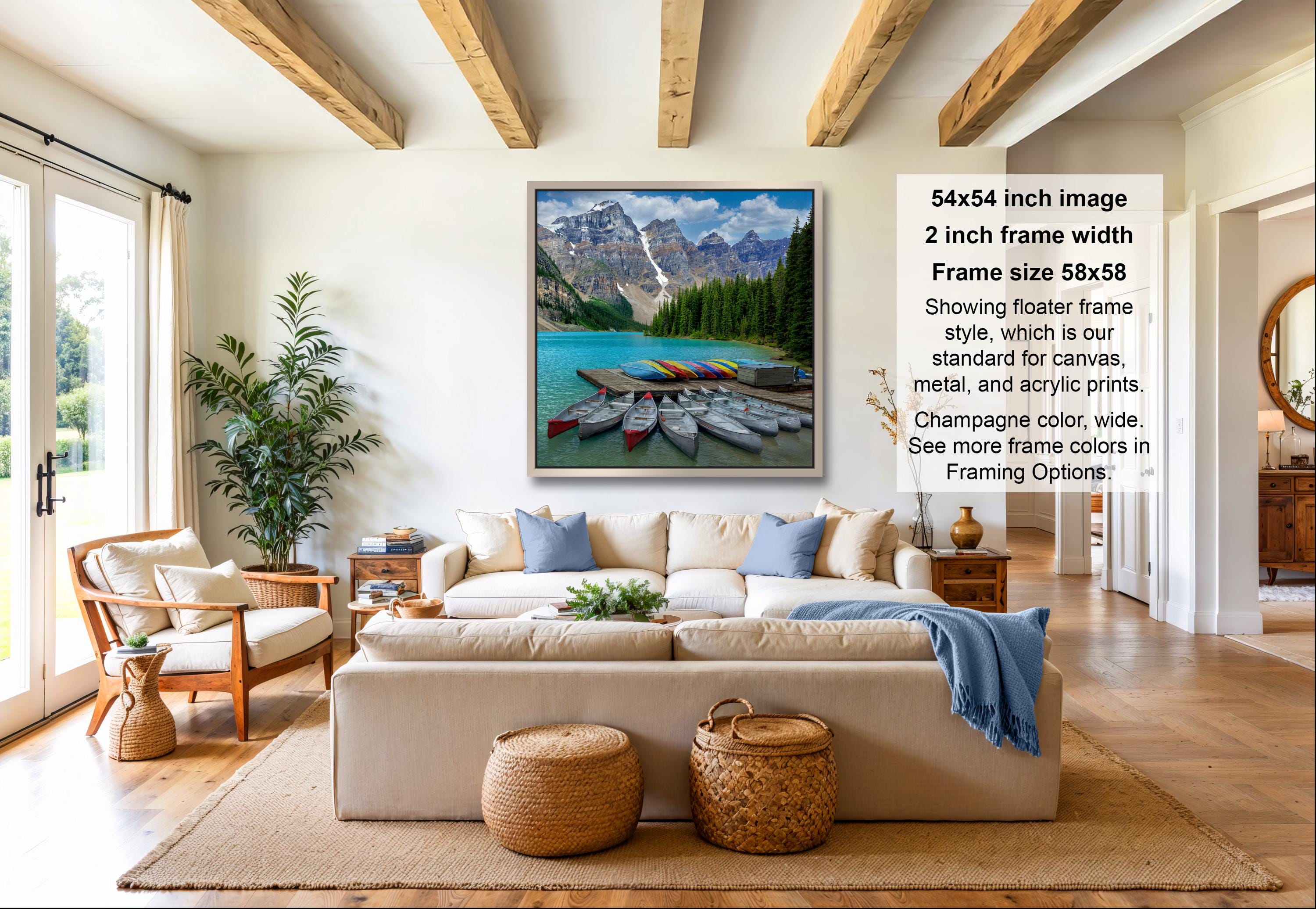 a living room with a large framed picture of a scenic mountain landscape hanging on the wall. The room is furnished with a sofa, chairs, and a coffee table, creating a cozy and inviting atmosphere.
